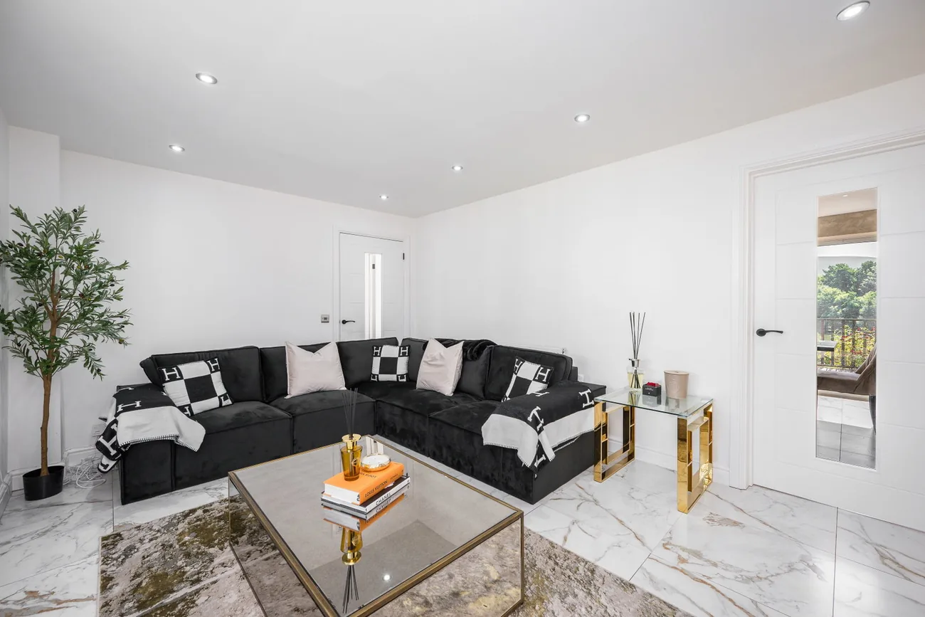 Sitting room with a corner sofa, marble-effect floor and gold accents