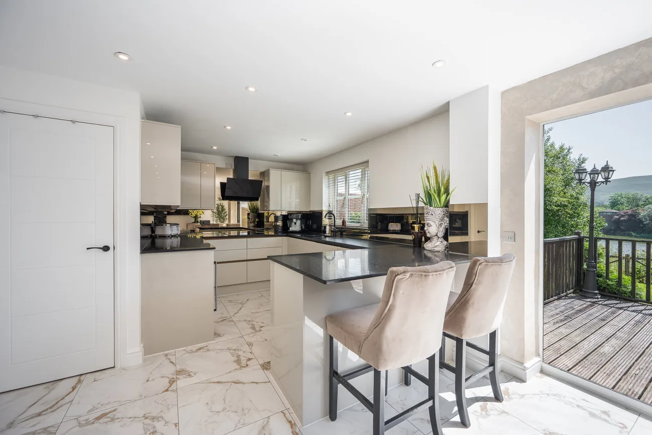 Kitchen island with breakfast seating beside open bi-fold doors to the deck