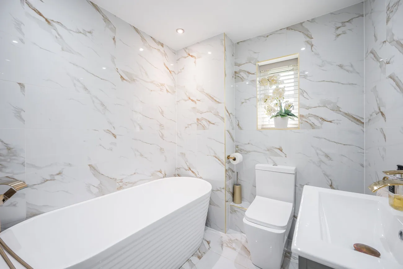 Family bathroom with a freestanding tub against marble-effect walls