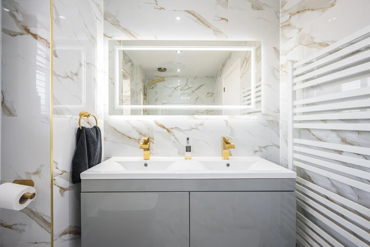 Vanity unit with twin basins, a backlit mirror and gold taps