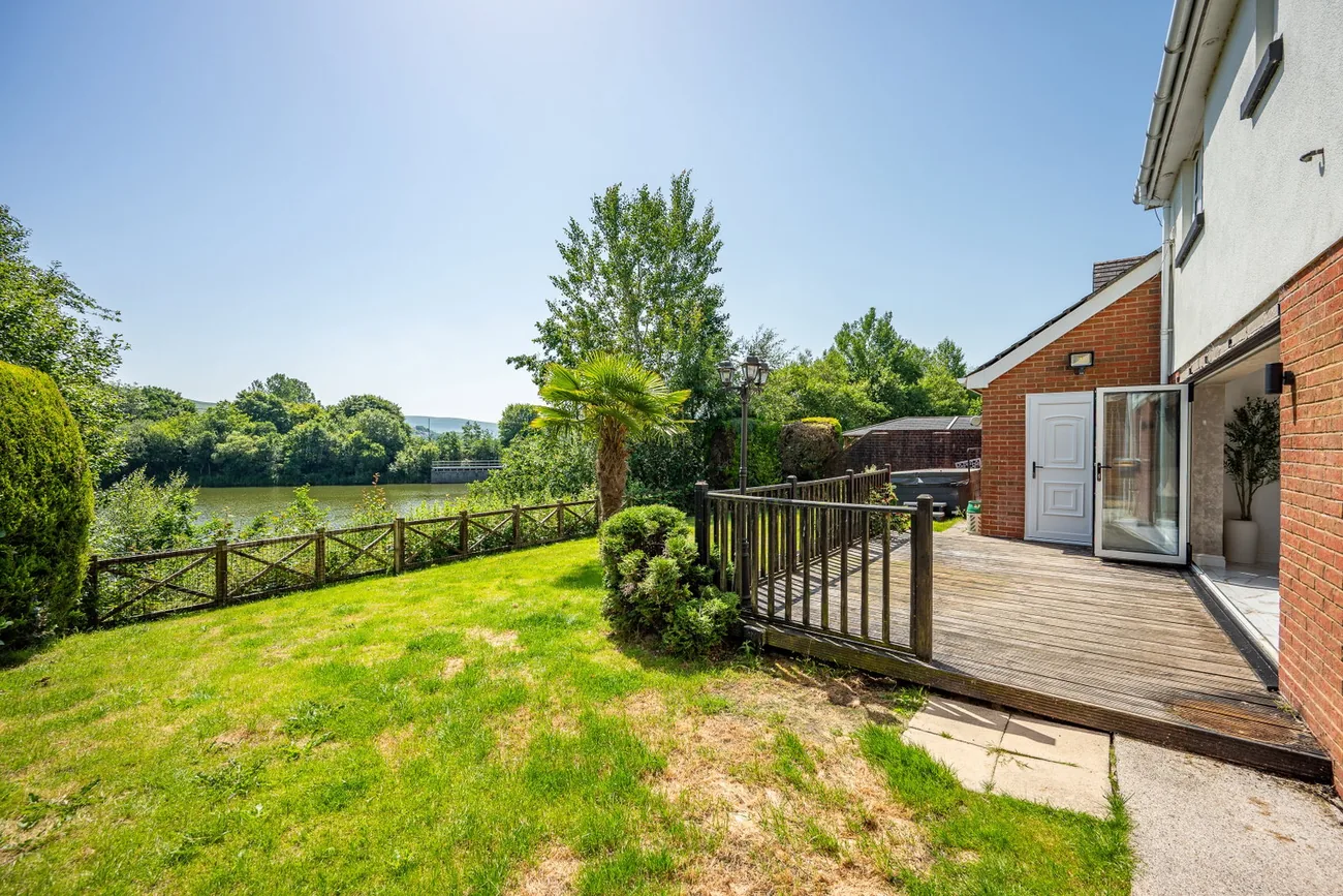 Raised timber deck and lawn with the lake beyond the fence