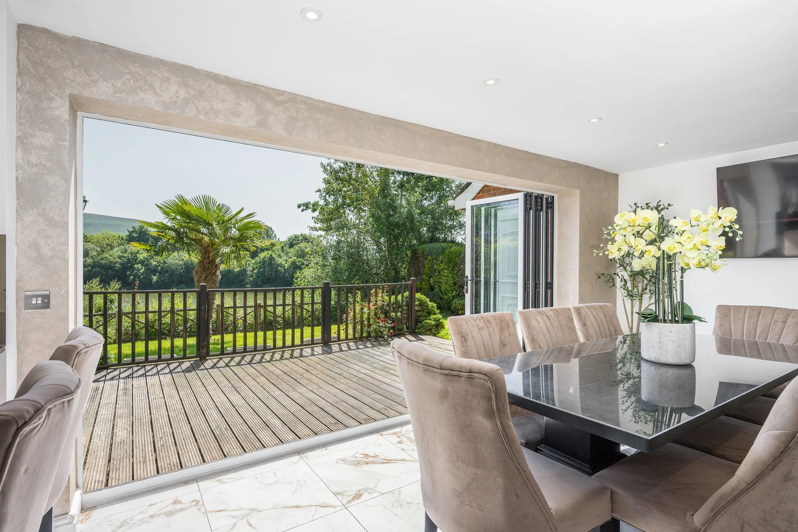 Open-plan dining area opening through bi-fold doors to the deck and garden